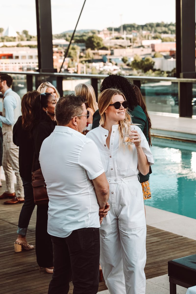 A man and a woman enjoying the Women's Edit event on the rooftop pool lounge at the Omni Hotel in Nashville, TN