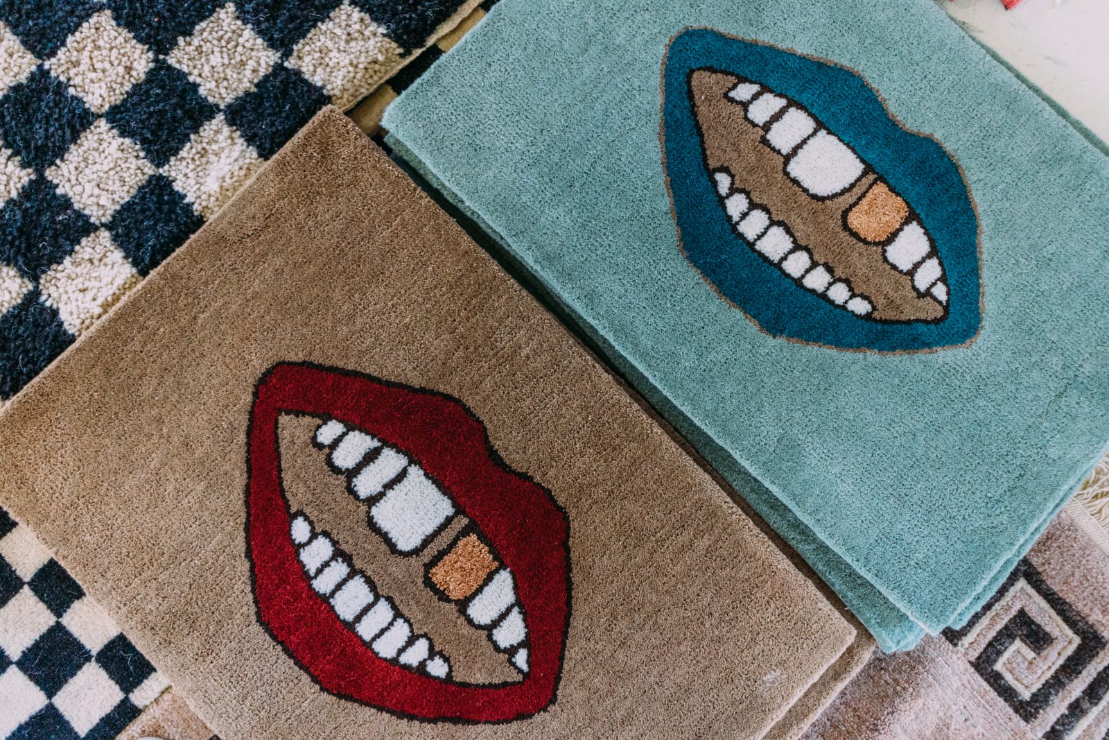 Hand tufted rugs from Relic Home. Gold tooth designs on blue with blue lips, and one with tan background and red lips